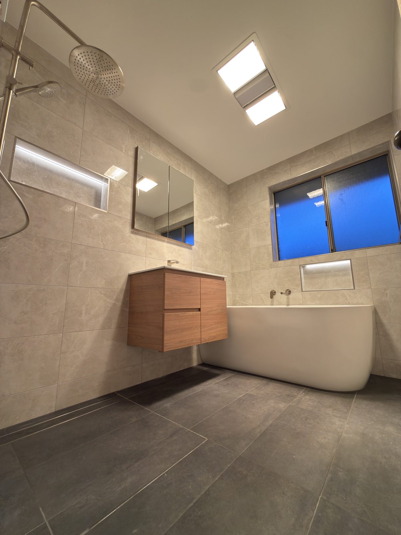 Renovated bathroom with an LED lit shower niche and ceiling heat and exhaust unit