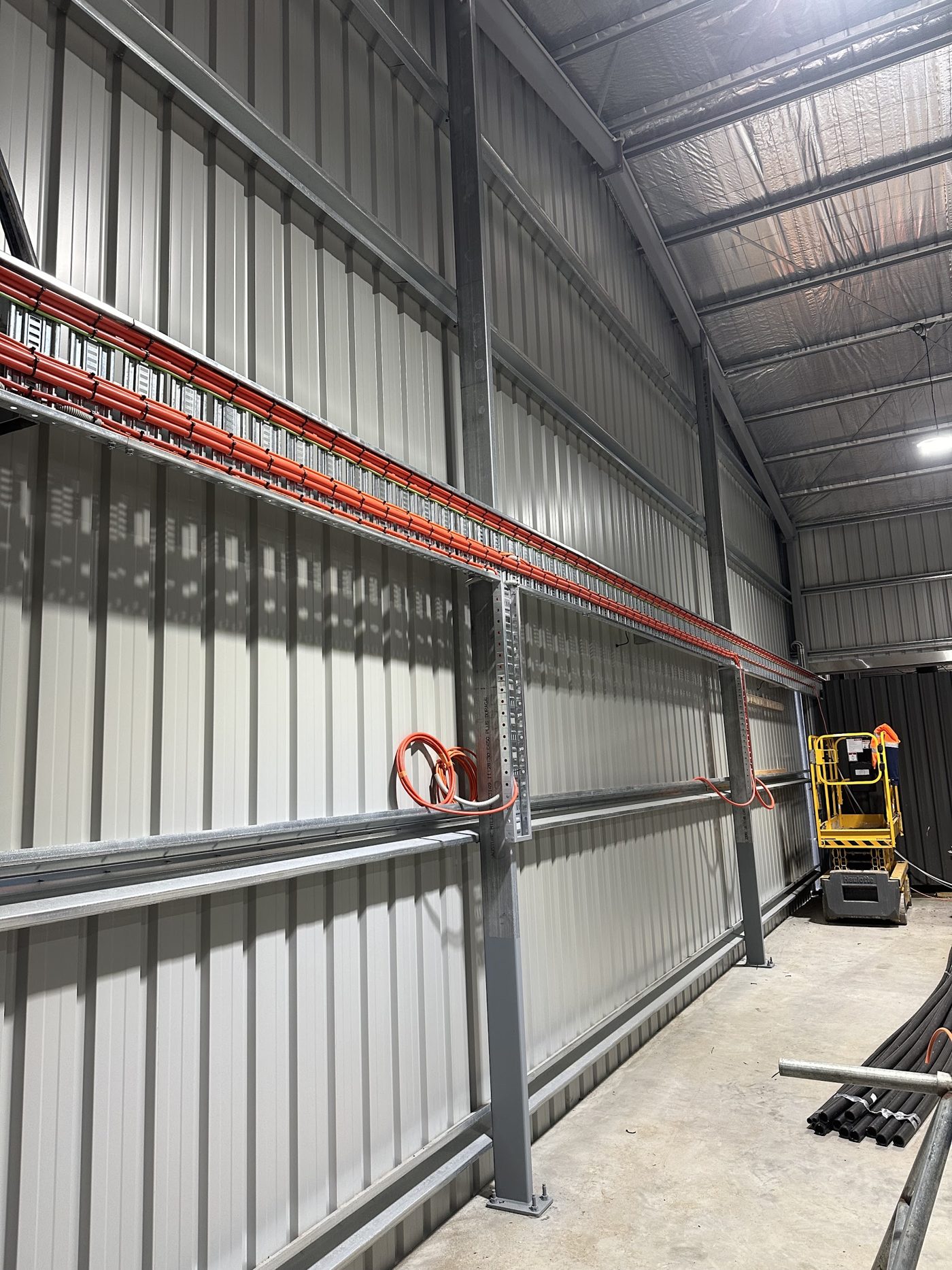 Red cable tray running the length of a steel shed wall