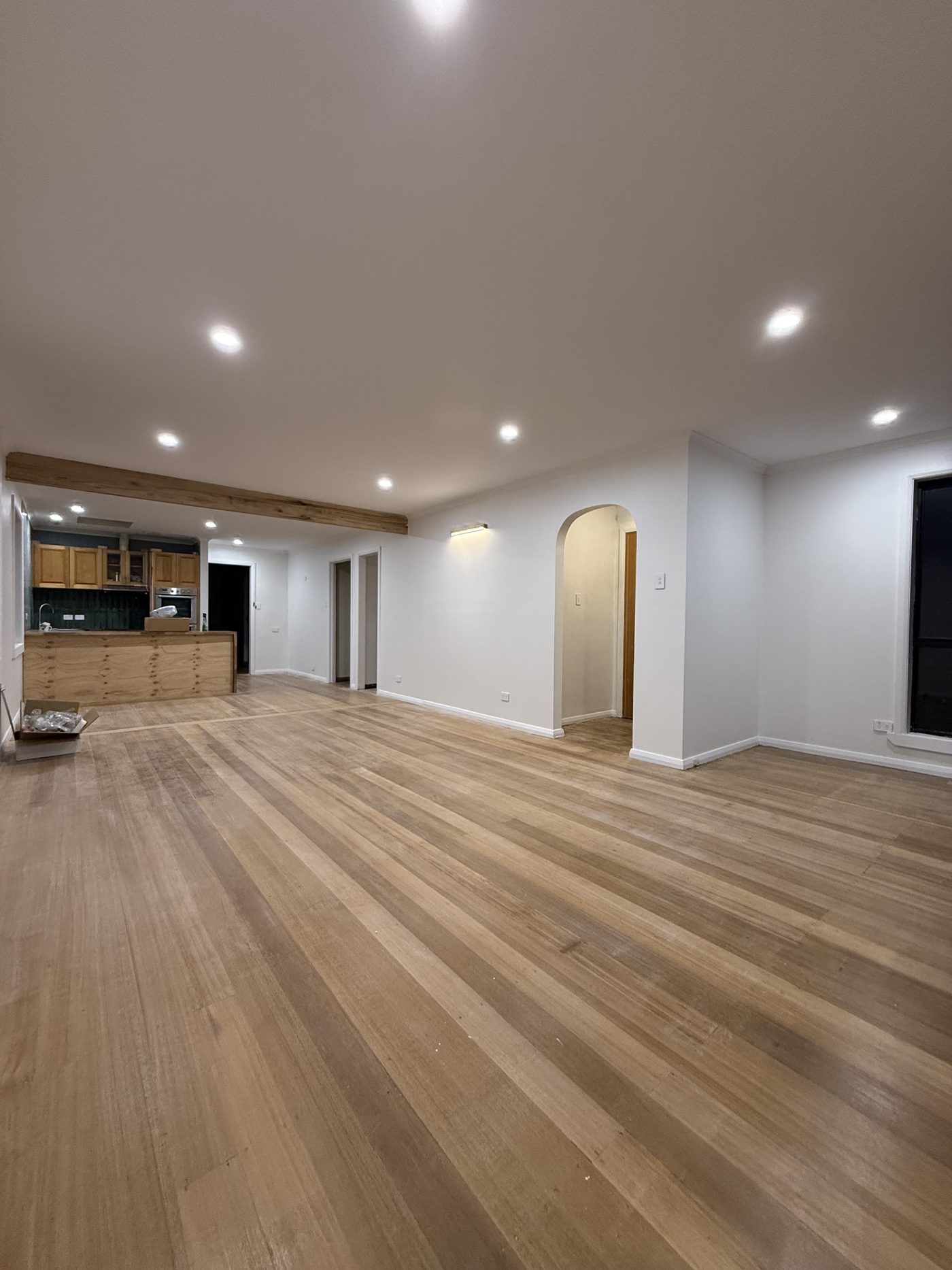 Open plan living room and kitchen with downlights across the ceiling